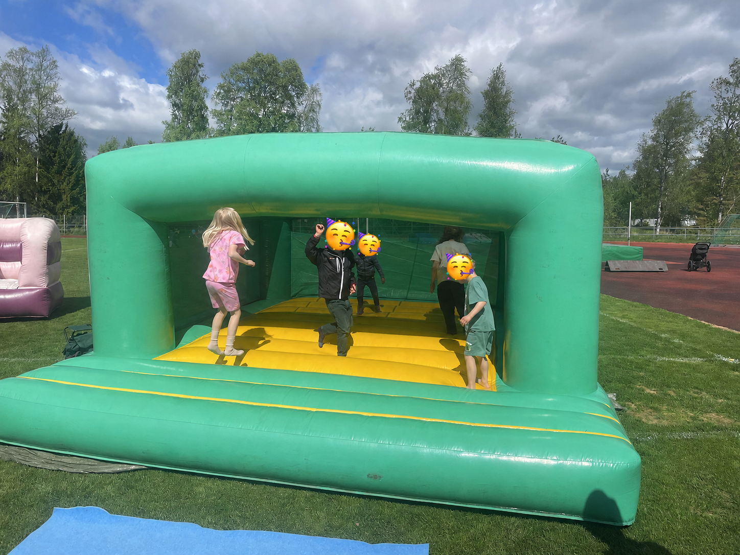 Lapset pomppimassa vihreässä pomppulinnassa, kaikilla on hauskaa sekä menoa riittää!