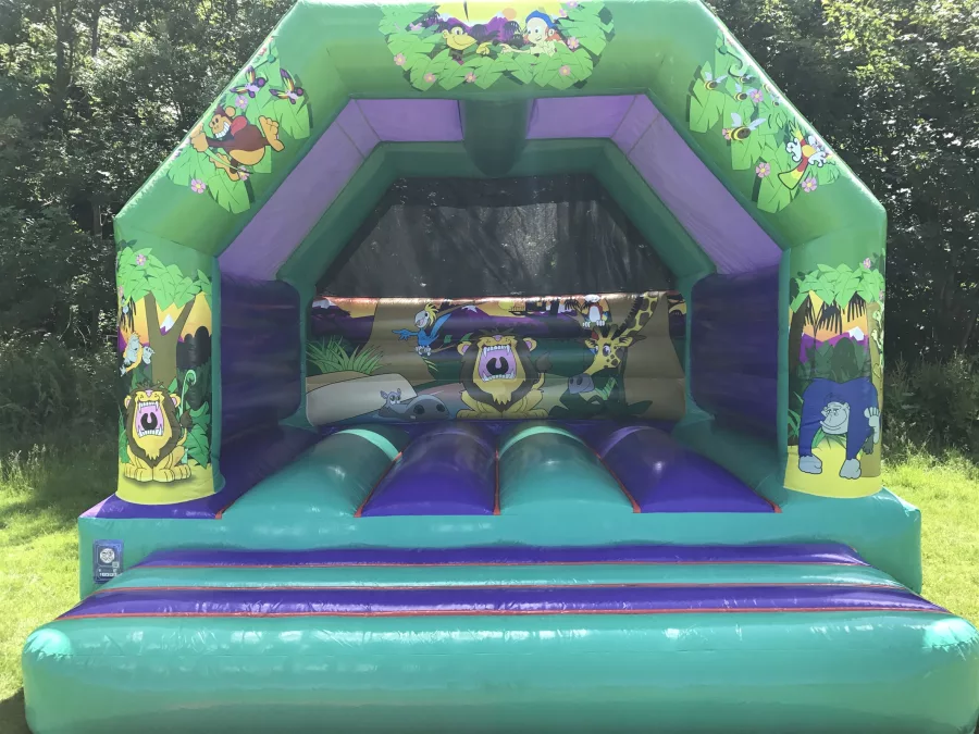 Viidakkolinna-pomppulinna vihreillä ja ruskeilla väreillä, viidakkomaisilla koristeilla ja seikkailuteemalla